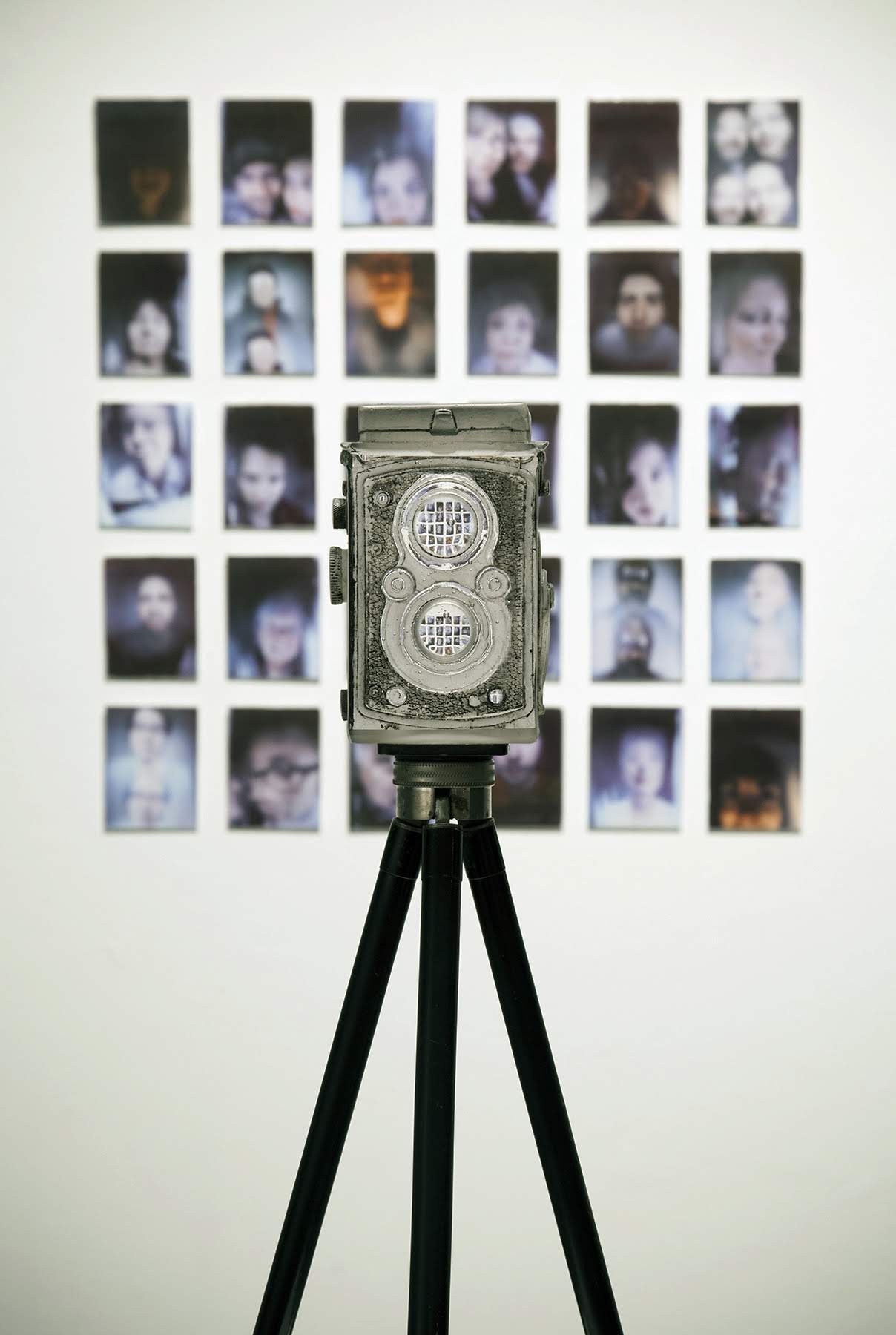 TITLE: “Derealization” MEDIUM: Glass, Polaroid film, Ceramic decals, antique tripod METHOD: Cast glass, fused glass, experimental photographic process, polished, digital process SIZE: Camera - 6”h x 5”w x 4.25”d. Wall Installation- 36”x36” DATE: 2015 PHOTO: Josh Hershman